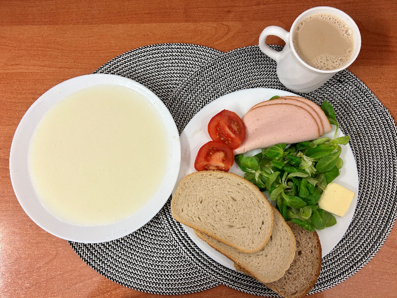 Na zdjęciu: Kasza manna na mleku, Kawa zbożowa z mlekiem, Chleb mieszany pszenno-żytni, Chleb Graham, Masło extra 82%, Filet zapiekany drobiowy, Pomidor, Roszponka